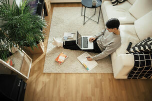  A person is sitting on the floor with a computer.