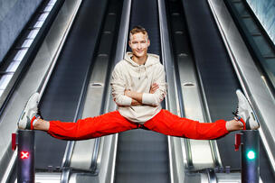Ung man i spagat vid metrostations rulltrappor.