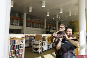 A man plays the trumpet and a woman plays the flute in Töölö Library.