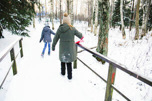 Lapsiperhe kävelee talvisessa puistossa.