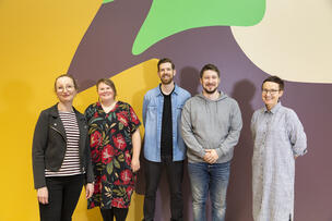 Five employees of Kalasatama library in front of the library's colorful wall.