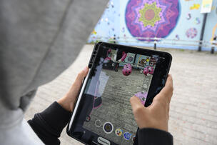 Poika huppu päässä pelaa pallopeliä ipadilla. 