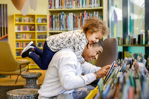 A man and a child choose children's books in the Myllypuro library's children's area. 