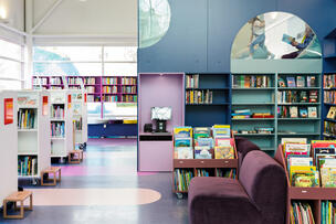 Blue-toned bookshelves and a reading loft in Pikku Huopalahti Library's main hall.