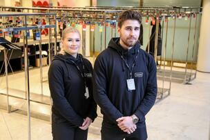 Kaksi Stadin AO:n turvallisuusalan opiskelijaa seisoo Helsingin kaupungintalon aulan naulakoiden edessä.