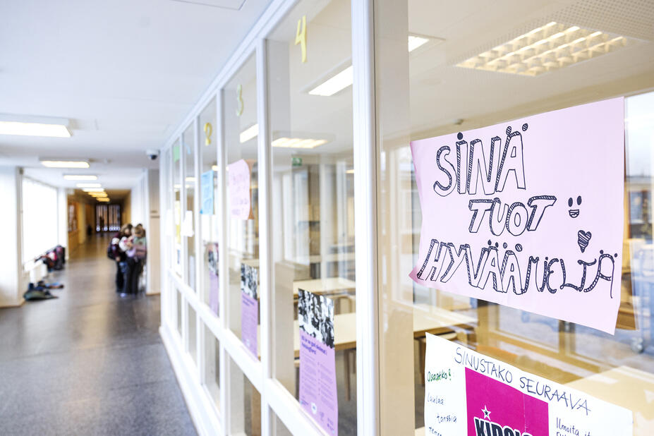 Koulun käytävän lasiseinässä lappu, jossa lukee "sinä tuot hyvää mieltä"