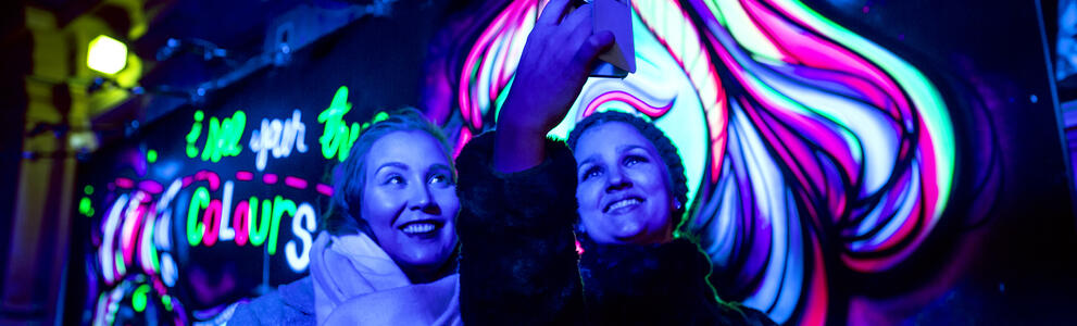 Lux Helsinki 2018. A winter’s night. Women taking a selfie over fluorescent art.