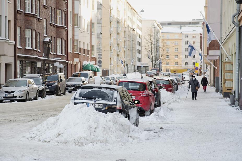 Parked cars in a snowy Helsinki street.