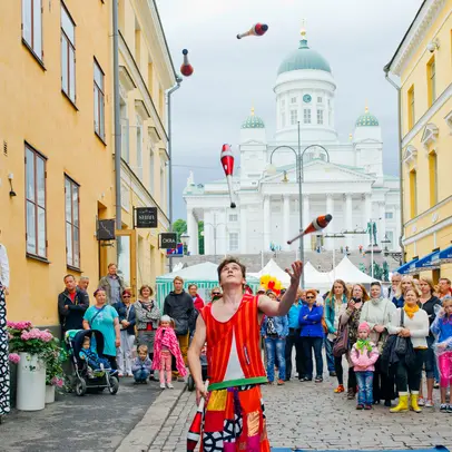 Yleisö katselee jonglöörin temppuja Helsingin torikortteleissa.